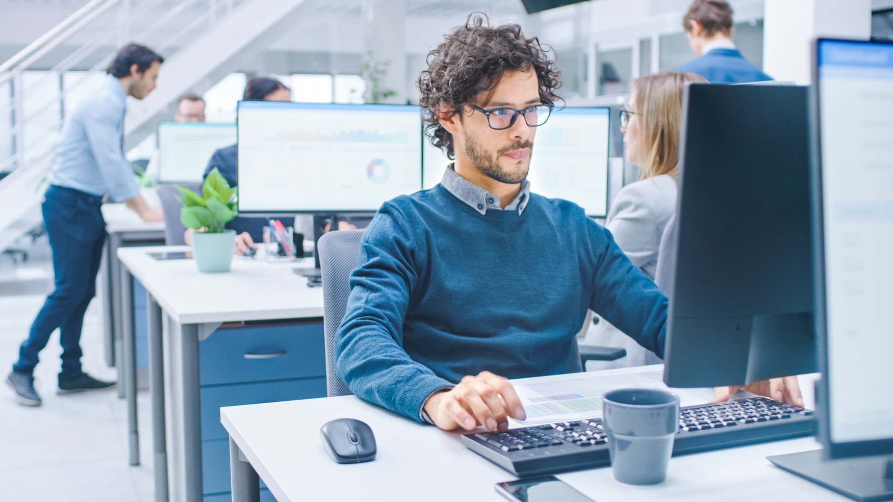 Collaborateur concentré devant son écran dans un open space lumineux